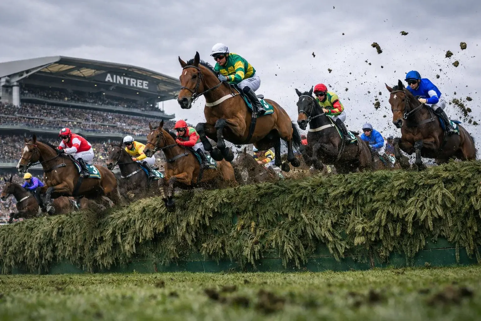 Large field of horses jumping a famous Aintree fence during the Grand National steeplechase